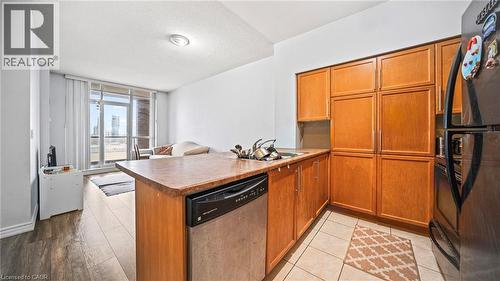 Kitchen with brown cabinetry, black appliances, expansive windows, a textured ceiling, and a peninsula - 388 Prince Of Wales Drive Unit# 1609, Mississauga, ON - Indoor Photo Showing Kitchen With Double Sink