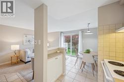 Kitchen featuring light tile patterned flooring, electric stove, hanging light fixtures, and light countertops - 