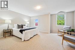 Bedroom featuring light carpet, multiple windows, and a textured ceiling - 