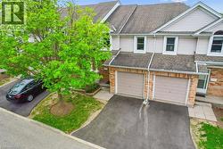 Multi unit property with driveway, brick siding, a garage, and a shingled roof - 