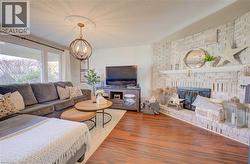 Great room with a brick fireplace, hardwood / wood-style floors, a textured ceiling, and an inviting chandelier - 
