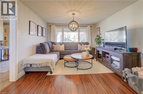 Great room featuring wood-type flooring, a textured ceiling, and an inviting chandelier - 47 Manor Drive, Kitchener, ON - Indoor Photo Showing Living Room