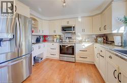 Kitchen with light wood-type flooring, appliances with stainless steel finishes, light stone countertops, and crown molding - 