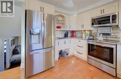 Kitchen featuring light wood-type flooring, light stone counters, ornamental molding, and stainless steel appliances - 