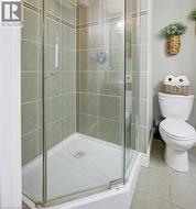 ensuite Bathroom with walk in shower, toilet, and tile patterned floors - 