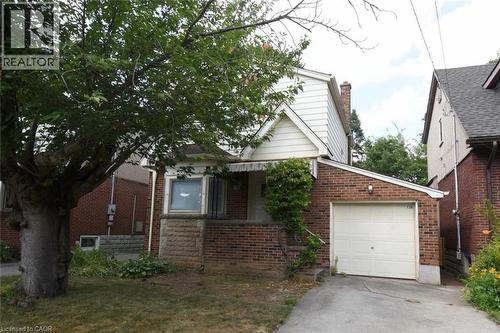 Bungalow-style house featuring a garage, brick siding, concrete driveway, and a chimney - 136 Glen Road, Hamilton, ON - Outdoor