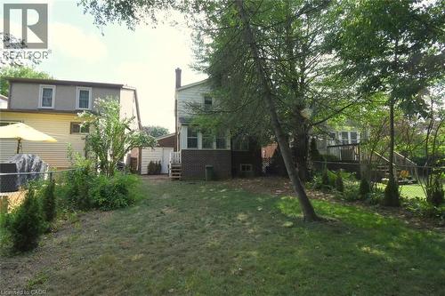 Rear view of property featuring a fenced backyard, a wooden deck, and brick siding - 136 Glen Road, Hamilton, ON - Outdoor