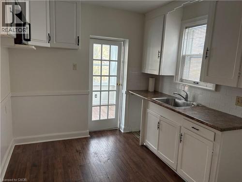 Kitchen with white cabinetry, dark wood-type flooring, dark countertops, and black microwave - 136 Glen Road, Hamilton, ON - Indoor Photo Showing Kitchen