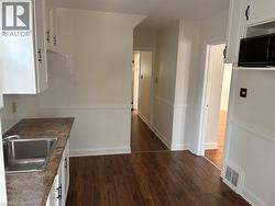 Kitchen featuring white cabinetry, dark wood-type flooring, dark countertops, and decorative backsplash - 
