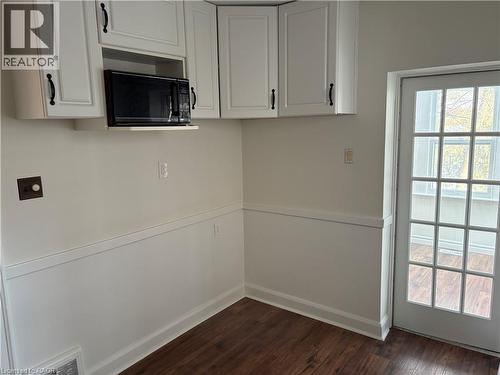 Kitchen with black microwave, dark wood finished floors, and white cabinets - 136 Glen Road, Hamilton, ON - Indoor Photo Showing Other Room