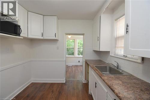 Kitchen featuring white cabinetry, dark wood finished floors, dark countertops, and decorative backsplash - 136 Glen Road, Hamilton, ON - Indoor Photo Showing Kitchen