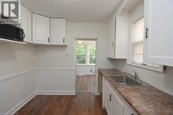 Kitchen featuring white cabinetry, dark wood finished floors, dark countertops, and decorative backsplash - 