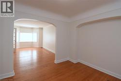 Spare room featuring light wood-type flooring and arched walkways - 