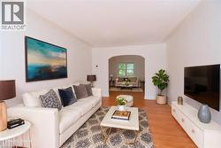 Living area with light wood-style floors and arched walkways - 