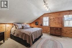 Bedroom with wood walls, a textured ceiling, track lighting, and vaulted ceiling - 