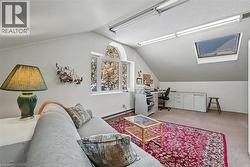 Carpeted home office featuring lofted ceiling, a skylight, and a baseboard radiator - 