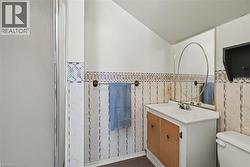 Bathroom with vanity, vaulted ceiling, an enclosed shower, and a wainscoted wall - 