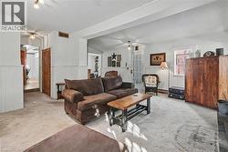 Living room featuring a textured ceiling, a wainscoted wall, and light colored carpet - 