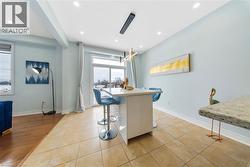 Kitchen with a kitchen breakfast bar, decorative light fixtures, light tile patterned floors, and a center island - 