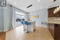 Kitchen featuring a breakfast bar area, decorative light fixtures, decorative backsplash, light stone counters, and dark wood finish cabinetry - 