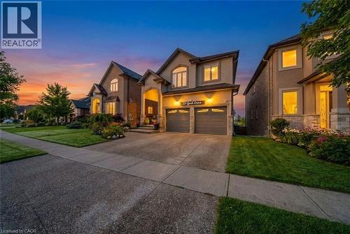 French country inspired facade with a front lawn, driveway, an attached garage, stucco siding, and stone siding - 59 Greti Drive, Hamilton, ON - Outdoor With Facade