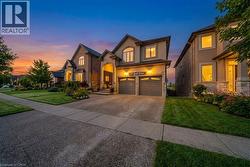 French country inspired facade with a front lawn, driveway, an attached garage, stucco siding, and stone siding - 
