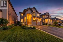 View of front of home featuring stucco siding, a yard, driveway, and a garage - 