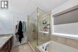 Full bathroom with vanity, a garden tub, a shower stall, and light tile patterned floors - 