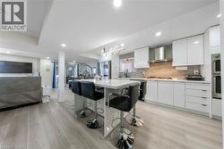 Kitchen featuring modern cabinets, open floor plan, a kitchen bar, white cabinetry, and a center island - 