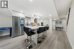 Kitchen with white cabinetry, smart refrigerator, modern cabinets, light wood finished floors, and a center island - 