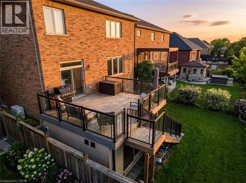 Back of house at dusk with a fenced backyard, a deck, and brick siding - 59 Greti Drive, Hamilton, ON - Outdoor With Deck Patio Veranda With Exterior