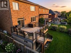 Back of house at dusk with a fenced backyard, a deck, and brick siding - 