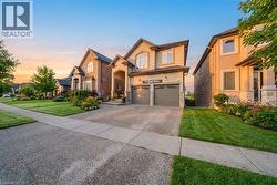 View of front facade with a front lawn, an attached garage, asphalt driveway, stucco siding, and stone siding - 