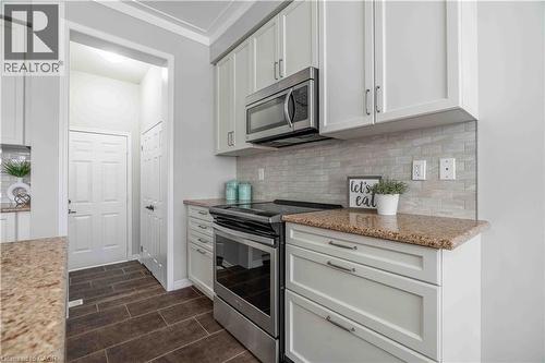 Kitchen with appliances with stainless steel finishes, decorative backsplash, and light stone counters - 115 Larry Crescent, Caledonia, ON - Indoor Photo Showing Kitchen