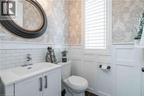 2-pc powder room featuring wallpapered walls, a wainscoted wall, vanity, and a decorative wall. - 115 Larry Crescent, Caledonia, ON - Indoor Photo Showing Bathroom