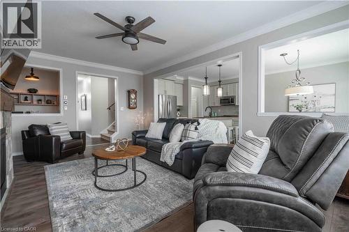 Living room with crown molding, a ceiling fan, wood finished floors, and access to stairway, planning centre and kitchen/dining areas. - 115 Larry Crescent, Caledonia, ON - Indoor Photo Showing Living Room