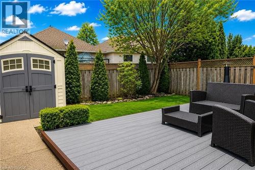 Spacious backyard featuring a gray composite deck, manicured lawn, and a light-colored storage shed with gray double doors - 27 Beaverton Drive, Hamilton, ON - Outdoor With Deck Patio Veranda