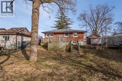 Back of property featuring a wooden deck, brick siding, a fenced backyard, and an outbuilding - 