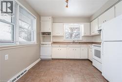 Kitchen with white appliances, white cabinetry, decorative backsplash, light tile patterned floors, and light countertops - 