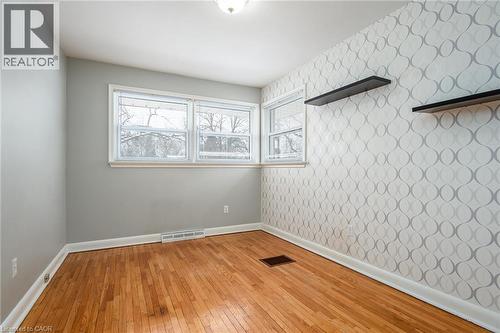 Unfurnished room featuring light wood-style floors, healthy amount of natural light, and wallpapered walls - 120 Fourth Avenue, Kitchener, ON 