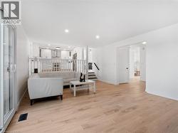 Living room with recessed lighting, visible vents, stairway, and light wood finished floors - 