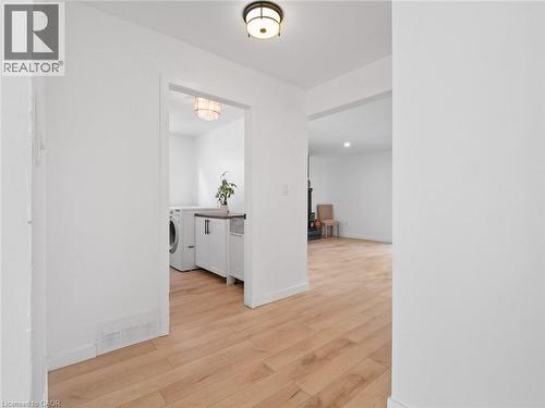 Hallway featuring light wood-style flooring, washer / dryer, baseboards, and visible vents - 24 Keefer Road, Thorold, ON - Indoor