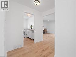 Hallway featuring light wood-style flooring, washer / dryer, baseboards, and visible vents - 