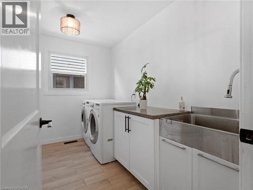 Washroom featuring visible vents, light wood finished floors, a sink, cabinet space, and separate washer and dryer - 24 Keefer Road, Thorold, ON - Indoor Photo Showing Laundry Room