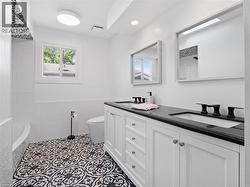 Bathroom featuring visible vents, a sink, toilet, and double vanity - 