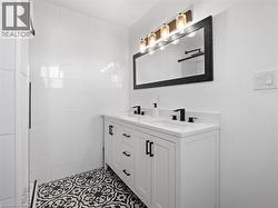 Full bathroom featuring double vanity, a sink, and a tile shower - 