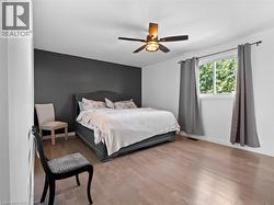 Bedroom featuring a ceiling fan, wood finished floors, baseboards, and visible vents - 