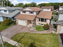 Split level home featuring brick siding, a front lawn, roof with shingles, a residential view, and driveway - 