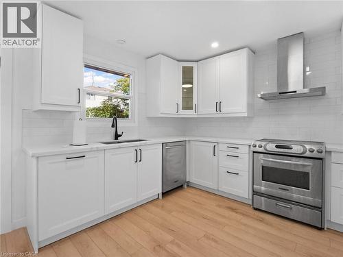 Kitchen with light countertops, a sink, stainless steel range with electric cooktop, light wood finished floors, and wall chimney range hood - 24 Keefer Road, Thorold, ON - Indoor Photo Showing Kitchen