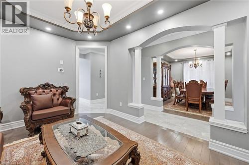 Living room featuring a chandelier, a tray ceiling, crown molding, hardwood / wood-style floors, and decorative columns - 456 Valridge Drive, Ancaster, ON - Indoor